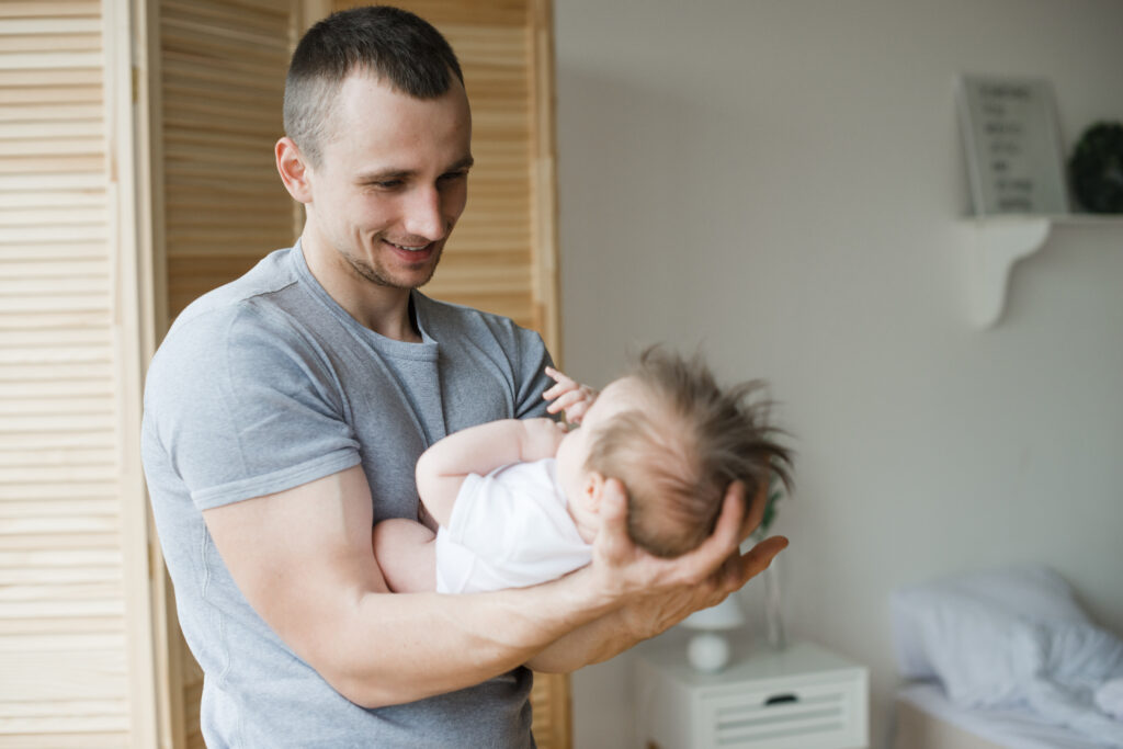 smiling dad holding baby hands