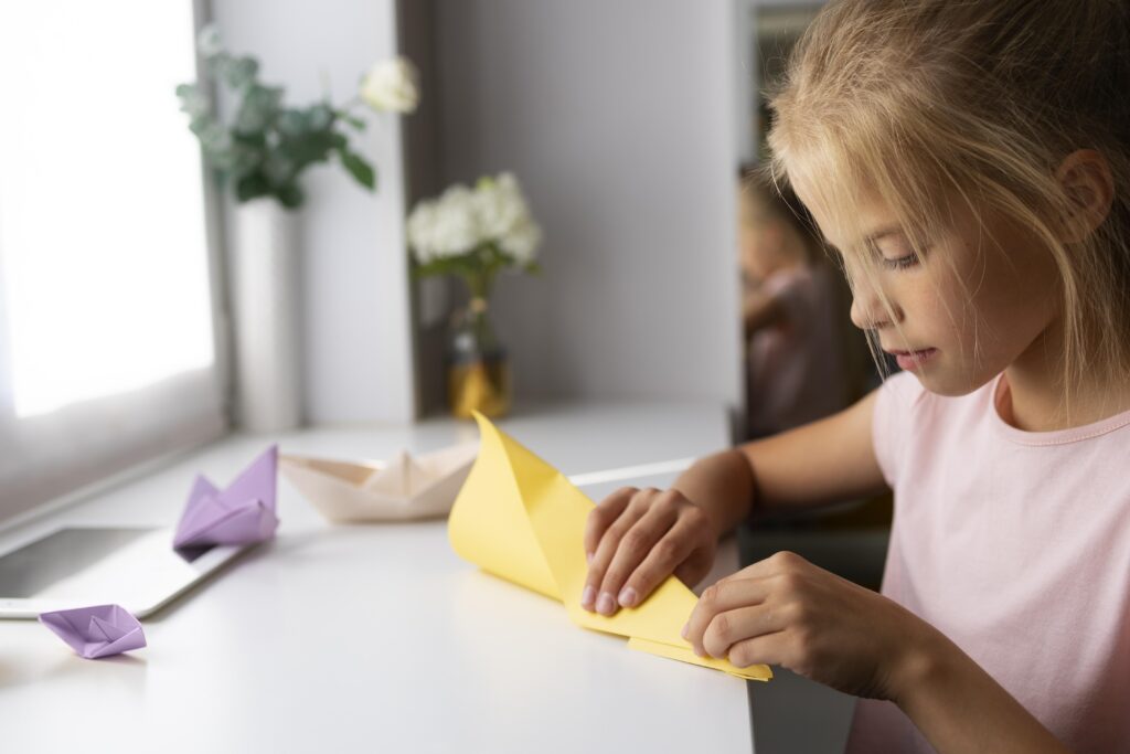 little girl playing with origami paper home
